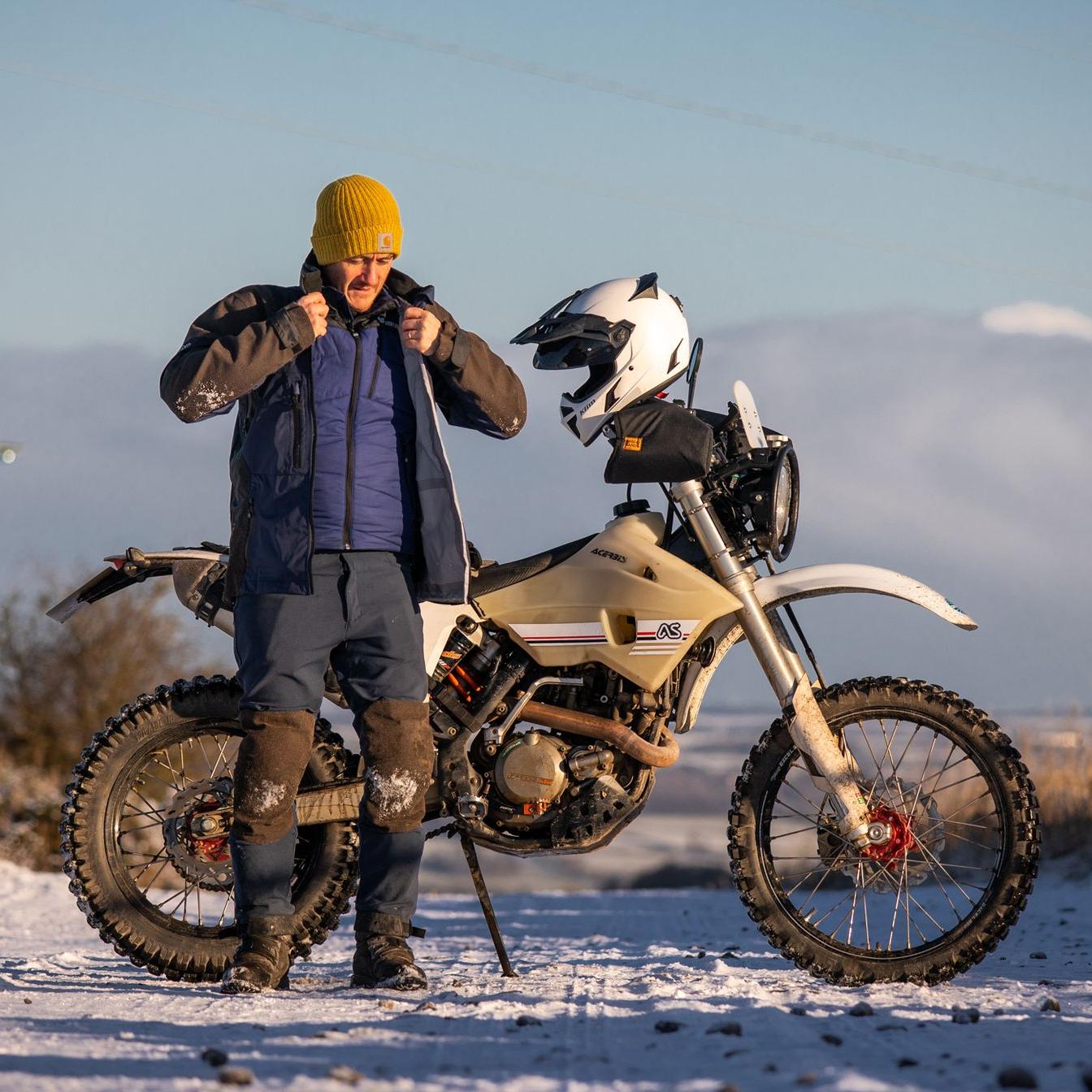 man putting singletrack jacket on with linesman pant adventure spec outdoor gear