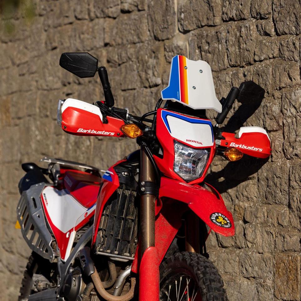 adventure spec mini fairing mouted on red honda crf 300l leaning against stone wall in sunshine